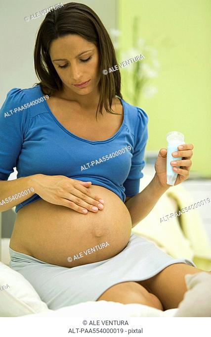 Pregnant woman applying moisturizer to belly