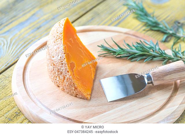 Wedge of Mimolette cheese on the wooden board