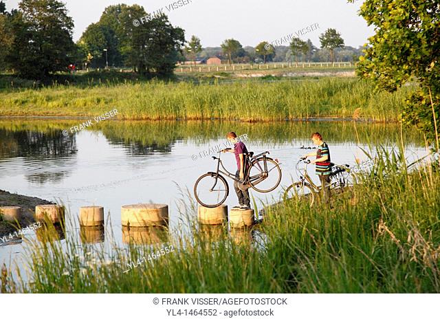 Boys with bicycles crossing a lake, Netherlands