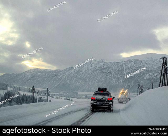 Driving through snowy white road and landscape in Norway. Car in front