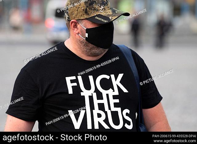 15 June 2020, Saxony, Dresden: A participant in a rally of the Islam- and xenophobic Pegida movement wears a black mouth-and-nose cover on the Altmarkt