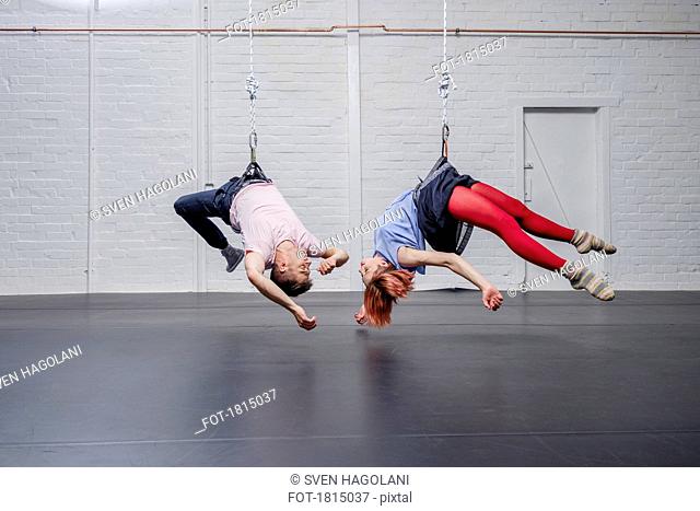 Modern aerialist dancers performing, hanging upside-down