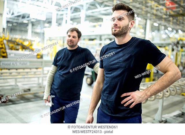 Two confident colleagues having a break in a modern factory