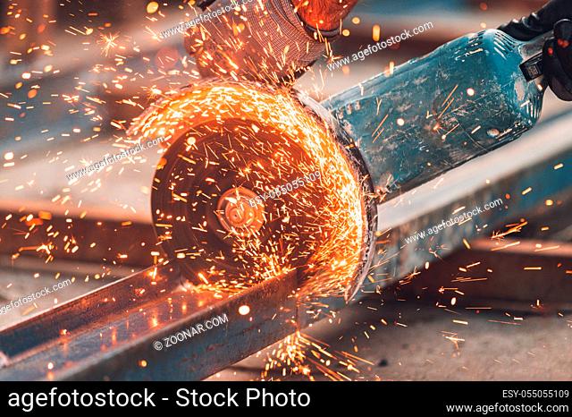 Construction worker using Angle Grinder cutting Metal at construction site