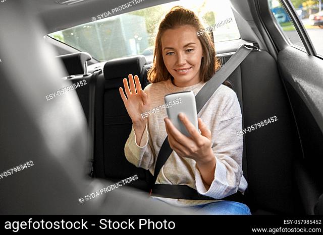 happy woman in car having video call on smartphone