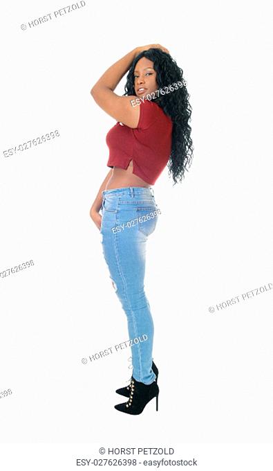 A beautiful African American woman standing in jeans in profile for.white background with one hand on head.