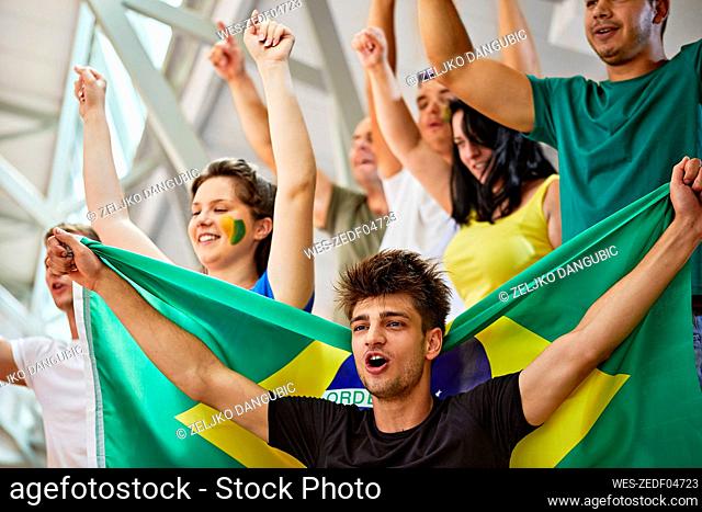 Fans with Brazil Flag shouting together at sports event in stadium