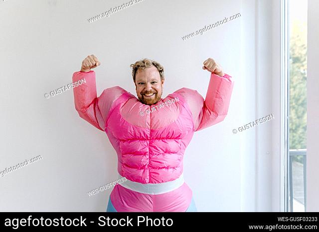 Proud man wearing pink bodybuilder costume flexing his muscles