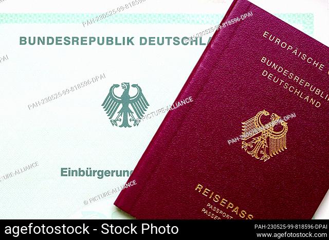 SYMBOL - 22 May 2023, Berlin: A certificate of naturalization from the Federal Republic of Germany (l) and a German passport lie on a table