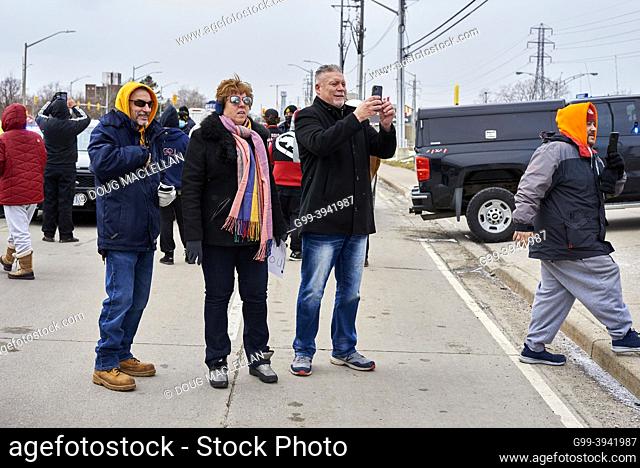 Three people look at a police barrier on College Street on 12 February in Windsor, Ontario on day six of the Freedom Convoy blockade of the Ambassador Bridge