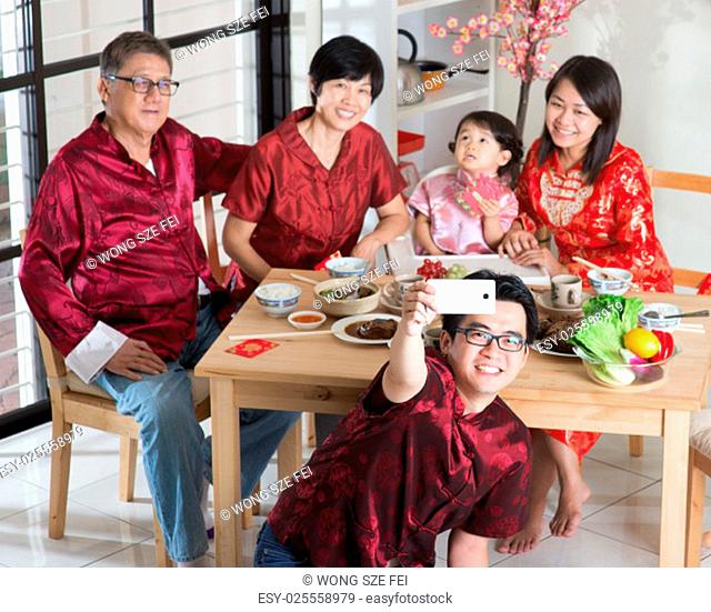 Chinese New Year, reunion dinner. Happy Asian Chinese multi generation family with red cheongsam selfie while dining at home