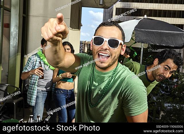 Man smiling and pointing at cameras while at St Patrick's day party