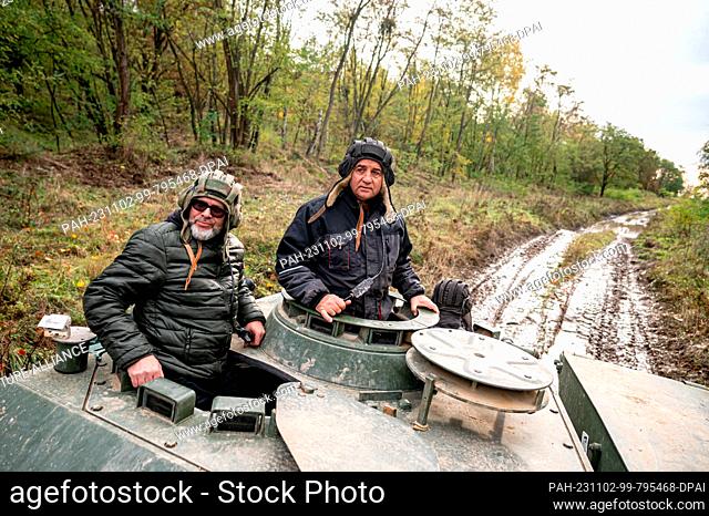 02 November 2023, Brandenburg, Wustermark/Ot Elstal: Axel Heyse (M), owner of the Heyse tank driving school, drives with his driver in a Leopard 1 tank through...