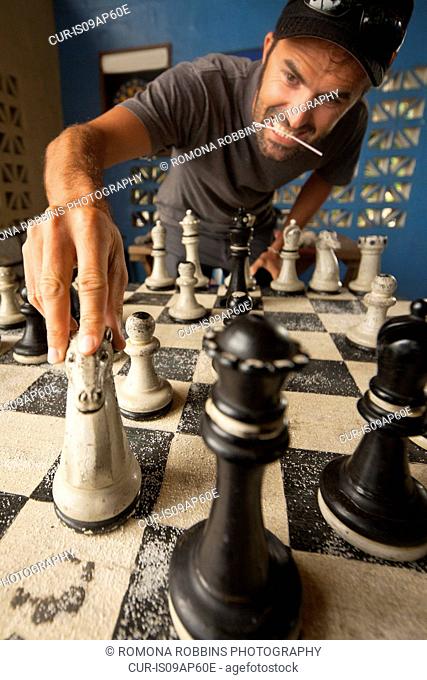 Mid adult man moving chess piece on giant chess board