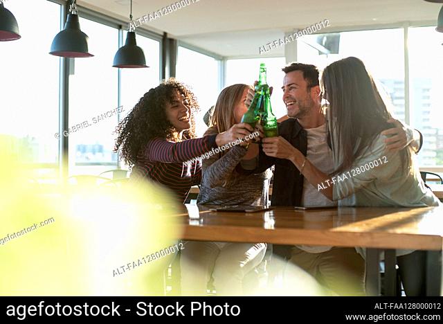 Smiling colleagues toasting drink bottles in office