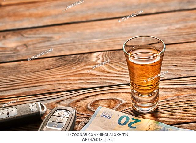 Glass of tequila or alcohol drink and car key on rustic wooden table with copy-space. Drink and drive and alcoholism concept