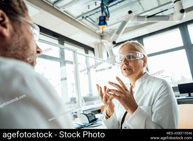 Senior scientist explaining to colleague in laboratory