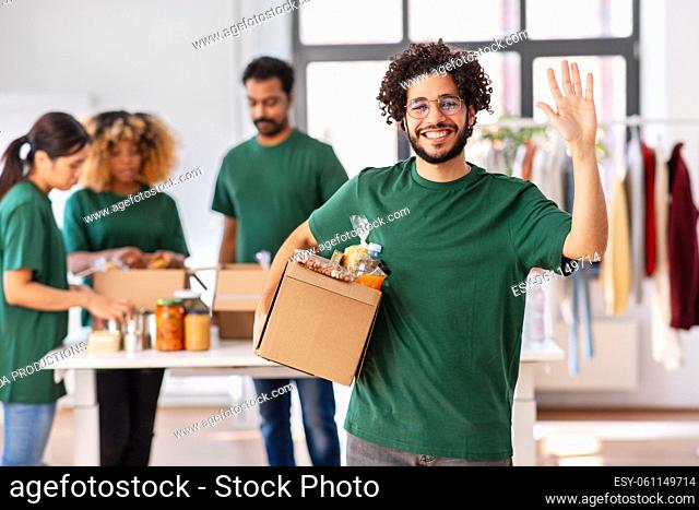 male volunteer with food in box waving hand