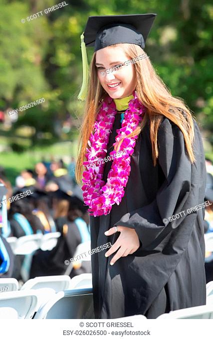 Happy college graduate walking between chairs outdoors