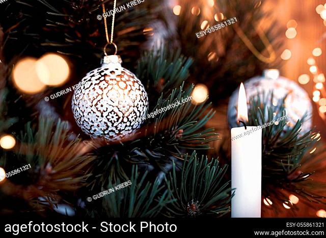 Christmas tree decoration with balls and candlelight. Close-up with golden bokeh and short depth of field. Atmospheric background for a christmas concept