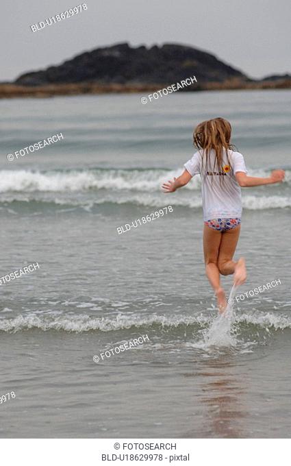 Girl running through water, Wickaninnish Beach, Vancouver Island, Canada