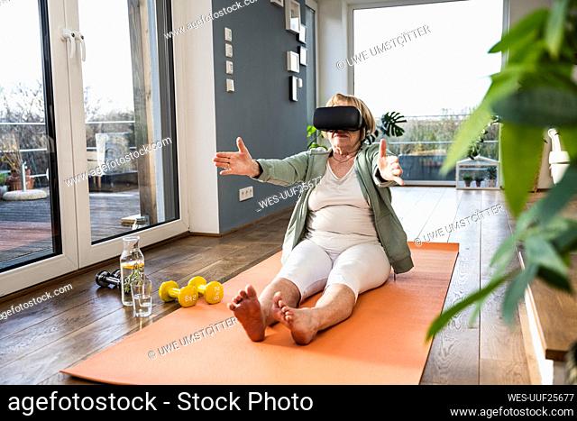 Senior woman wearing virtual reality simulator exercising at home