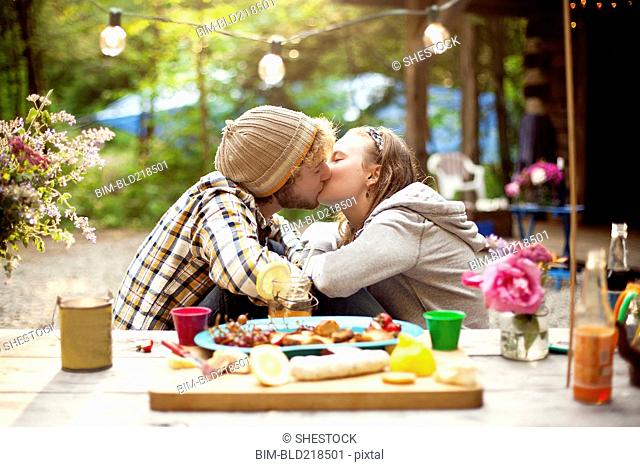 Couple kissing at picnic table in forest