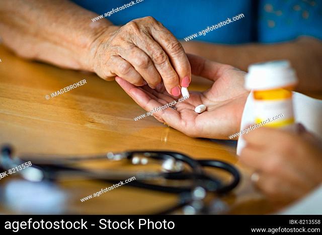 Senior adult woman taking medicine pill from doctors palm