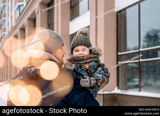 Father carrying son outside building in winter