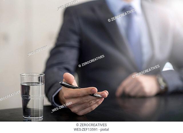Businessman holding pen next to glass of water