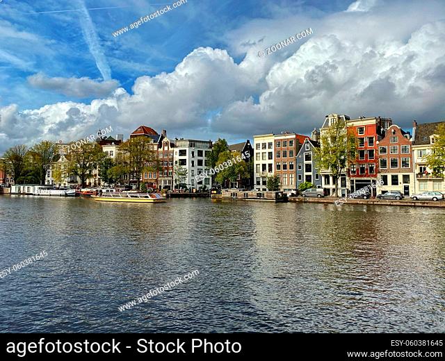Amsterdam canal with typical dutch houses and houseboats, boats in the evening with beautiful water reflections, Holland, Netherlands