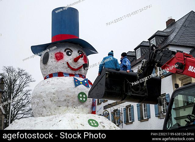 17 February 2023, Bavaria, Bischofsgrün: Horst (l) and Berndt Heidenreich have just lit a whistle for the giant snowman in the Franconian village