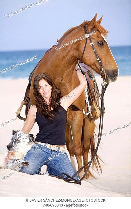 Woman on the beach with horse and dog