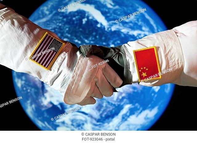 An American astronaut shaking hands with a Chinese astronaut