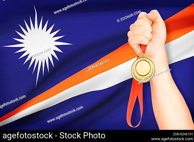 Sportsman holding gold medal with flag on background - Marshall Islands