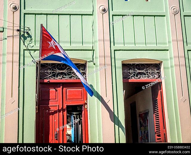 Cuban flag with door and window facade at colonial Cuban house in Santiago de Cuba