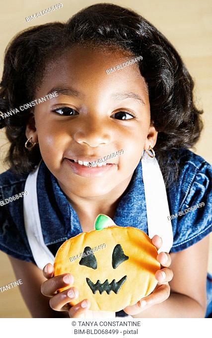 African girl holding Halloween cookie