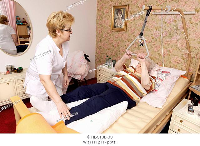 Geriatric nurse caring for old woman in bed