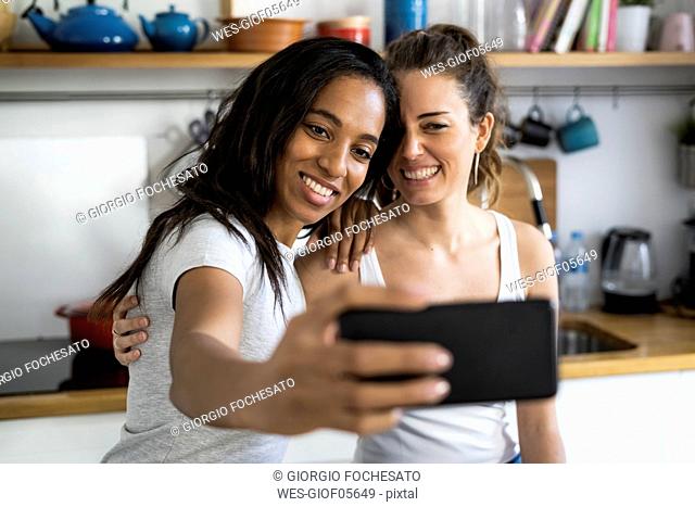 Two happy girlfriends taking a selfie at home