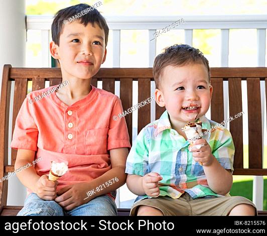 Young mixed-race chinese and caucasian brothers enjoying their ice cream cones