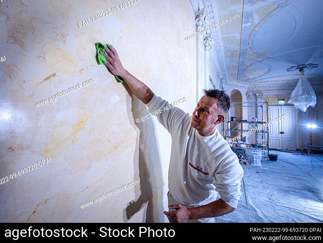 22 February 2023, Mecklenburg-Western Pomerania, Ludwigslust: Dirk Westphal from the company Guse Stuck und Restaurierung polishes a replica marble wall in the...