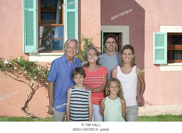 Portrait of three-generation family with two children 6-9 in front of house