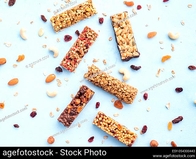 Granola bar on blue background. Set of different granola bars on white marble table. Shallow DOF. Top view or flat lay