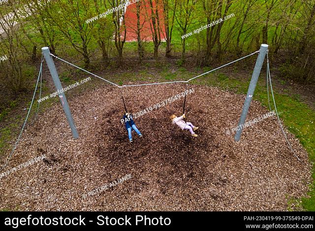 SYMBOL - 19 April 2023, Baden-Württemberg, Rottweil: Two girls swinging on a playground. Photo: Silas Stein/dpa. - Rottweil/Baden-Württemberg/Germany