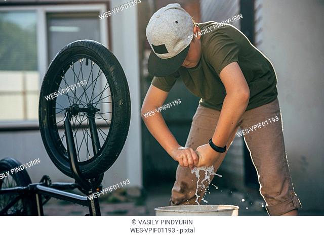 Boy cleaning bmx bike on yard