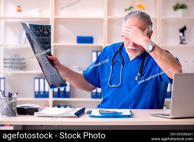 White bearded old doctor radiologist working in clinic