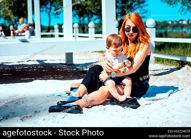 Mom and son rest on the sand near the lake, have fun