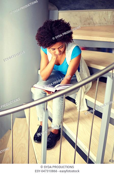 african student girl reading book on stairs