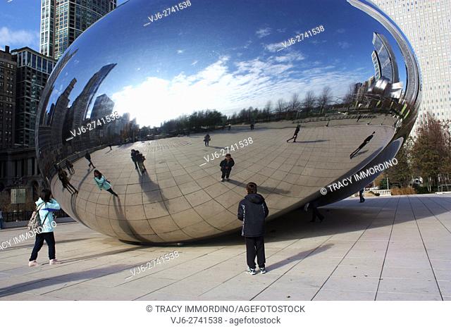 Tourists looking at their reflections in the Chicago Bean in Millennium Park in Chicago, IL, USA