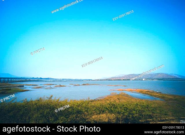 Panorama of lake landscape in Thailand with railway across the lake and mountain scene on background against summer blue sky in Lopburi province Pa Sak Jolasid...